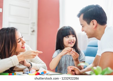 Girl daughter playing blocks toy over father and mother, happy family concept