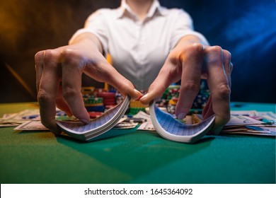 Girl Dealer Or Croupier Shuffles Poker Cards In A Casino On The Background Of A Table, Chips,. Concept Of Poker Game, Game Business