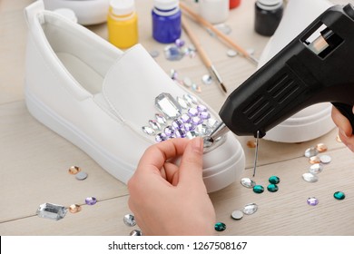 Girl Decorating Her Shoes With Lots Of Different Rhinestones Using A Hot Glue Gun. Cool DIY Custom Design Idea.