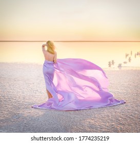 A girl in delightful dress admires the beautiful sunset the lake