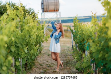 Girl In A Denim Jacket Walking In A Young Vineyard On The Back Burner Barrel For Wine