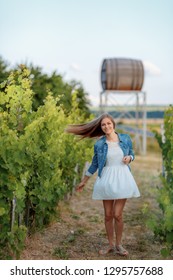 Girl In A Denim Jacket Walking In A Young Vineyard On The Back Burner Barrel For Wine