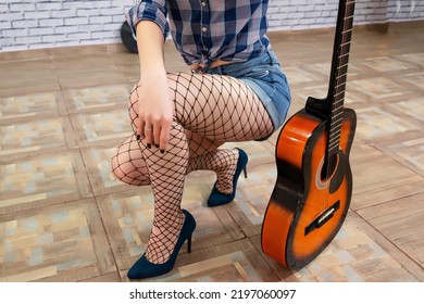 Girl In Denim Shorts And Fishnet Tights, With A Guitar. 80s Style, Theme Party, Close-up Photo Of Details.

