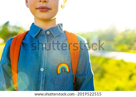 girl in denim t-shirt with rainbow symbol wear backpack in summer park outdoor