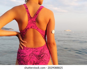 Girl With Diabetes Enters The Sea. On The Right Arm Is Placed White Sensor For Continuous Glucose Monitoring In Blood – CGM. Swimming  With This Type Of Sensor Is Possible