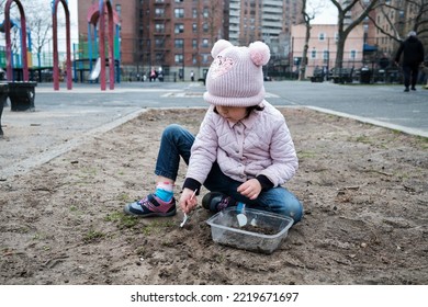 Girl Digging In The Dirt On The Playground On A Foggy Fall Day