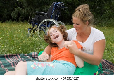 The girl is a disabled person with a helper sit on the grass. - Powered by Shutterstock