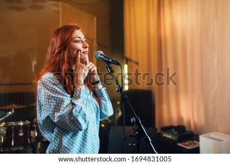 girl does exercises with lips at chants in vocal lesson near the microphone