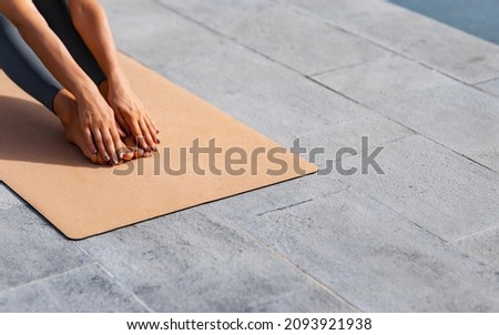 The girl does exercises and pulls her hands to her feet on the yogamat. Focus on yogamat
