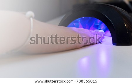 girl does manicure, ultraviolet lamp for manicure, female fingers under the ultraviolet lamp
