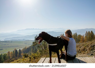 A girl with a dog enjoying the view of Tatra Mountains from Zar- mountain in Little Beskids, Poland
