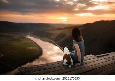 A girl with a dog at sunset. walk with a pet. Jack Russell Terrier and owner in nature look at a beautiful view 