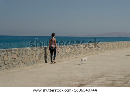 girl with a dog walking along the sea on the waterfront