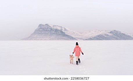 a girl with a dog in winter on the background of a mountain. White labrador in the snow running with a man - Powered by Shutterstock