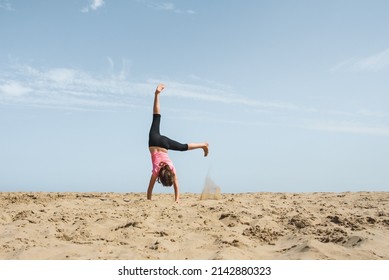 Girl doing a cartwheel in the sand on the beach