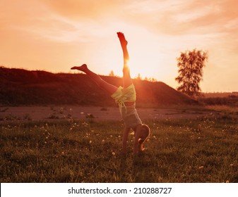 girl doing a handstand in a meadow 