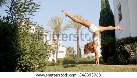 Girl doing a handstand on grass field. Slow motion shot of young african woman doing stunts on grass. 