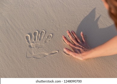 girl doing imprint with the hand in white sand - Shutterstock ID 1248090700