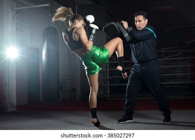 Girl Doing Knee Kick Exercise During Kickboxing Training With Personal Trainer