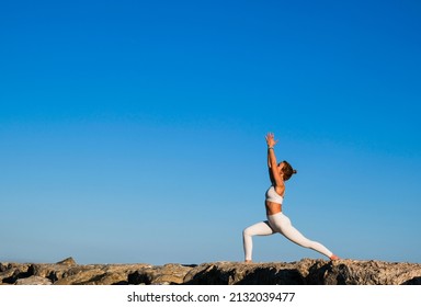 Girl Doing Yoga On The Rocks On The Beach