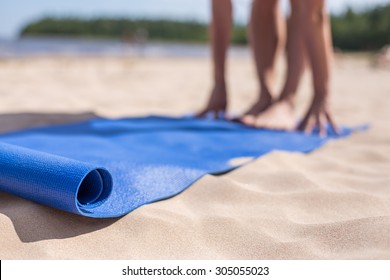 Girl doing yoga on sunny day at beach. Blue mat and blurred in background hands and feet - Powered by Shutterstock