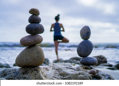 Girl Doing Yoga Tree Pose In Front Of Stacking Rocks