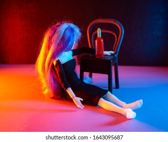 Girl doll sitting drunk on the floor near a chair with a closed bottle of wine. Red and blue lights. 