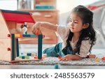 Girl, dollhouse and child play on floor, games and fantasy for brain development in home. Female person, toys and blocks on ground for entertainment, growth and toddler for education or learning