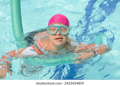 Girl with Down syndrome learns to swim, swimming teacher teaching a person with Down syndrome. pool lesson. Trisomy 21. Disability. Inclusion, 8, international day - Powered by Shutterstock