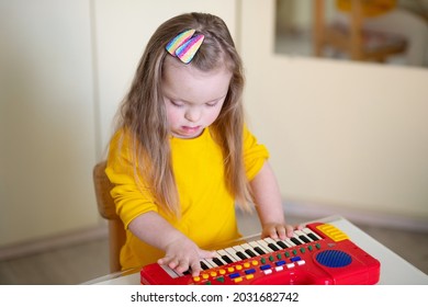 A Girl With Down Syndrome Playing A Children's Toy Piano, A Genetic Abnormality, An Extra Chromossome, A Disabled Child, A Psychiatric Anomaly.
