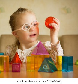 Girl with Down syndrome playing with geometrical shapes - Shutterstock ID 410365570