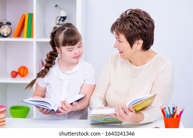 A Girl With Down Syndrome Is Reading A Book With Her Mom At Home. Everyone Has Their Own Book To Read.