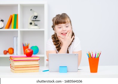 Girl with Down Syndrome studying on a tablet computer. Education for the disabled. Distance education
