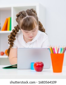 Girl with Down Syndrome studying on a tablet computer. Education for the disabled. Distance education