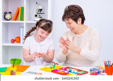 Girl with Down Syndrome works with her teacher at home - Shutterstock ID 1643241343