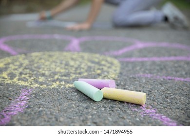 Girl Drawing By Chalk Colorful Pictures On The Ground. Detail Of Hands And Chalks.