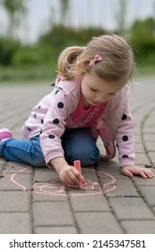 Girl Drawing With Chalk On The Sidewalk