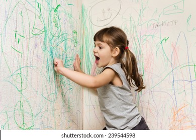 girl drawing with crayons on the wallpaper