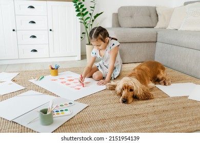 A girl draws hearts for his mother sitting on carpet floor in living room, cocker spaniel dog lying nearby - Powered by Shutterstock