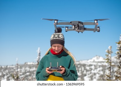 Girl with dreadlocksmanages the drone in winter snowy mountains.