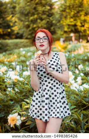 Girl in a dress with peas in a botanical garden. Flower garden on a bright summer sunny day