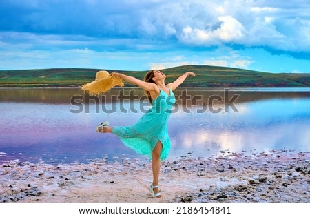 girl in a dress walks on the shore of a pink lake