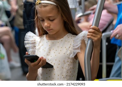 Girl In Dress Watching Video, Using Mobile Application In Smart Phone On Commuter Train. Internet Technology For Streaming Video On Mobile Phone In Subway Public Transportation.