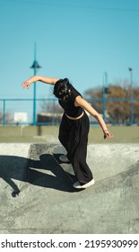 Girl Dressed All In Black Riding Her Skate On Skate Park Bowl Concrete. Vertical Photo