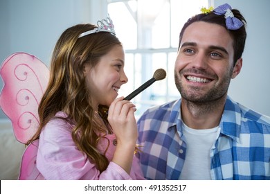 Girl dressed up in a fairy costume applying make-up on fathers face at home - Powered by Shutterstock