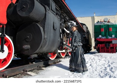 Girl Dressed As A Noblewoman Of The 19th Century Near A Steam Locomotive