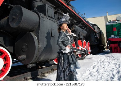 Girl Dressed As A Noblewoman Of The 19th Century Near A Steam Locomotive