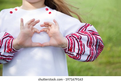 Girl dressed in vyshyvvanka making heart sign with hands. Traditional, ethnic, prints and ornaments. Vyshyvanka.Ukraine. Ukrainian Vyshyvanka`s day.Independence Day of Ukraine.