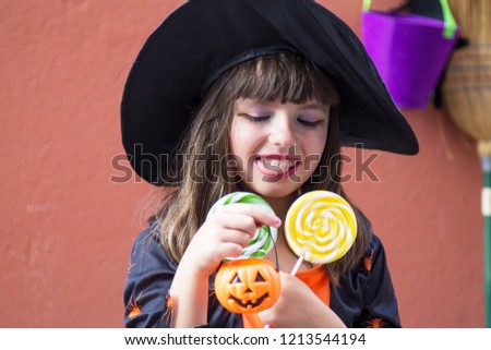 girl dressed up as a witch with candies and pumpkin. Halloween