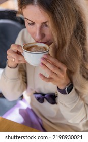 The Girl Is Drinking Cappuccino From White Cup On The Terrace